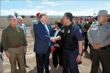  ??  ?? Trump greets Customs and Border Protection director of Field Operations Pete Flores as he stands with House Minority ieader hevin McCarthy (left) and other officials during a visit to the rp-Mexico border wall in CalexicoK — oeuters photo