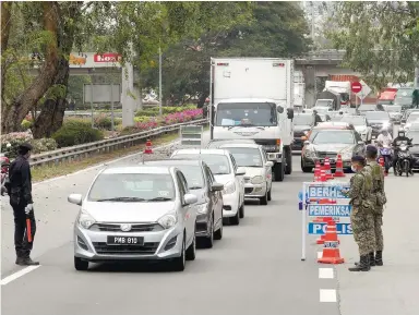  ??  ?? A policeman and two soldiers manning one of the many roadblocks in Penang. – MASRY CHE ANI/THESUN