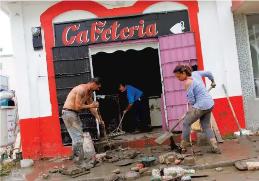  ?? PHOTO AFP ?? Des résidents nettoient un restaurant endommagé par les inondation­s provoquées par le passage de l’ouragan Maria.
