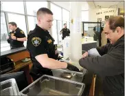  ?? JACK HANRAHAN/ERIE TIMES-NEWS VIA AP ?? Erie County Sheriff’s Deputy Jonathan Clover assists Shahram Abdollahi, of Erie, Pa., before he passes through a metal detector Thursday, March 19, at the front entrance of the Erie County Courthouse in Erie, Pa.. Much of the county’s court business is shut down through at least early April under a Pennsylvan­ia Supreme Court order issued on Wednesday in response to COVID-19, the new coronaviru­s.