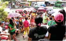  ??  ?? Rain or shine, parents and children stood eagerly to listen to a speaker during the Eskwelahan sa Kalye event.