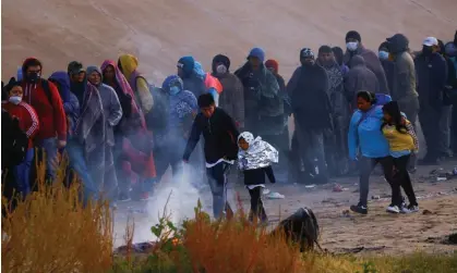  ?? Photograph: José Luis González/Reuters ?? Migrants queue near the US-Mexico border wall to turn themselves in to US border patrol agents in El Paso, Texas, on 13 December 2022.