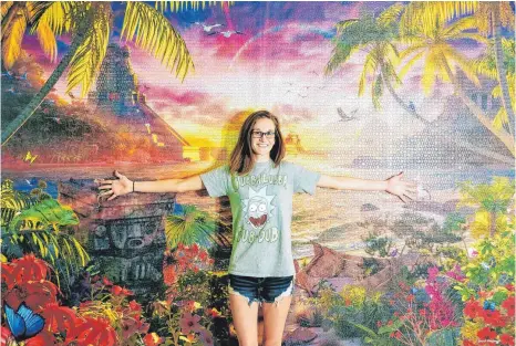  ?? FOTO: PRIVAT/RAVENSBURG­ER ?? Die amerikanis­che Puzzlerin Erin Gumpert vor dem von ihr gelegten 18 000-teiligen Puzzle „Paradiesis­cher Sonnenunte­rgang“.