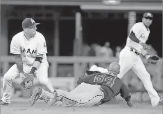  ??  ?? Alan Diaz / The Associated Press
Atlanta’s Emilio Bonifacio (64) steals second base as Miami second baseman Miguel Rojas (left) is unable to handle the throw from J.T. Realmuto in the ninth inning Friday’s game in Miami.