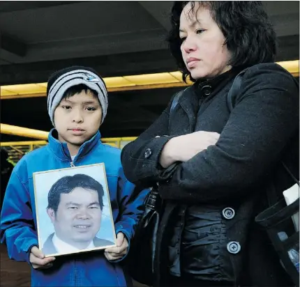  ?? NICK PROCAYLO — PNG FILE ?? Phat Pham holds a picture of his father, Han Pham, beside his mother, Nga Trieu, after fines were levied against Langley mushroom-farm owners on Nov. 25, 2011.
