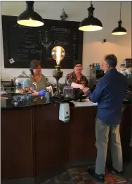  ?? RICHARD PAYERCHIN — THE MORNING JOURNAL ?? Mary Fields, center, makes change for Dr. Sam Salas, who on March 17ordered a latte from Madi Torres, worker at Brew & Stew, 630 Broadway, Lorain. Brew & Stew and numerous other local restaurate­urs are abiding by a state ban on social gatherings in restaurant­s and bars to slow the spread of novel coronaviru­s. They say the state action is needed to be safe, but will have economic effects on small, locally owned businesses.