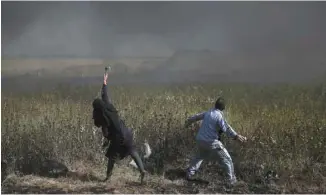  ?? KHALIL HAMRA ASSOCIATED PRESS ?? Des Palestinie­ns lancent des pierres vers les troupes israélienn­es à la frontière gazaouie vendredi.