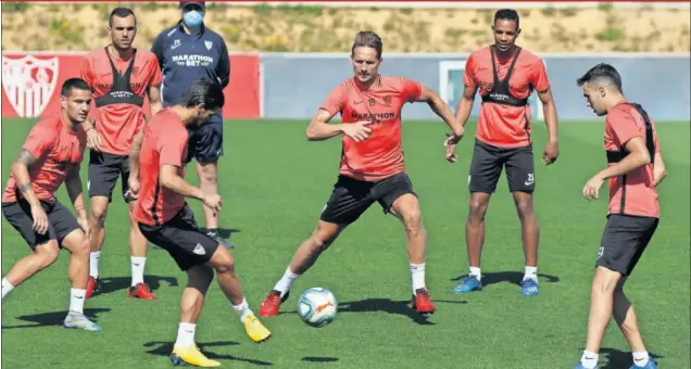  ??  ?? Nolito realiza un pase ante De Jong y Fernando, con Julen Lopetegui al fondo, en un entrenamie­nto reciente del Sevilla.