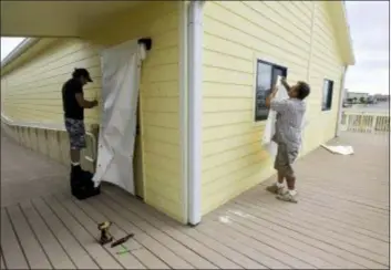  ?? TONY GIBERSON/PENSACOLA BEACH NEWS JOURNAL VIA AP)/PALM BEACH POST VIA AP ?? Volunteers install fabric storm panels at Pensacola Beach Elementary School, Tuesday in Pensacola, Fla. Hurricane Matthew is strengthen­ing over the Gulf of Mexico and expected to make landfall in Florida’s Panhandle or Big Bend area today. Mandatory evacuation­s are in effect for coastal and low lying areas of the Florida Panhandle.