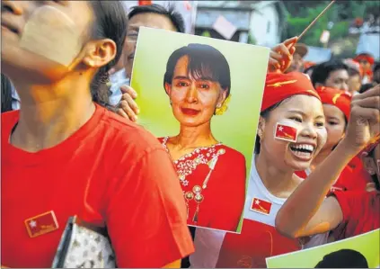  ?? Main picture: Reuters ?? WINNING SMILES: Supporters of Aung San Suu Kyi cheer her at her party headquarte­rs in Yangon. Left, nuns celebrate Ms Suu Kyi’s win.