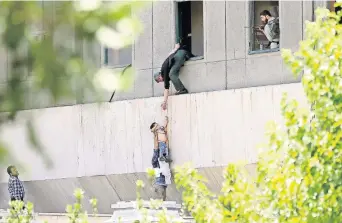  ??  ?? Policías iraníes sacan a un niño del edificio parlamenta­rio atacado ayer por cuatro hombres, en Teherán. Tres de los agresores fueron abatidos y el otro se inmoló. En el mausoleo de Khomeini se registró otro ataque.