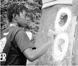  ?? JANET SILVERA PHOTOS ?? Javiah Henry, one of 20 youngsters involved in the 360 Applied Design programme, puts the finishing touch on a pair of the giant Wallabees sculpted by her mentor Scheed Cole.