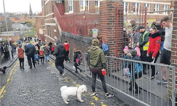  ??  ?? Parents and pupils leaving St Mary’s RC Primary School at home time, on to the narrow St Mary’s Lane.