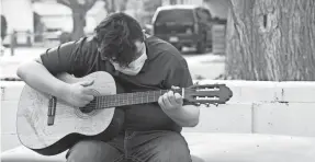  ?? PAUL RATJE/THE HECHINGER REPORT ?? Alan strums his guitar outside of his house. His involuntar­y outbursts due to Tourette syndrome have gotten him into trouble.