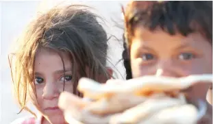  ??  ?? Displaced Iraqis receive food aid during the holy month of Ramadan at Al-Khazir camp for the internally displaced, located between Arbil and Mosul. (AFP)