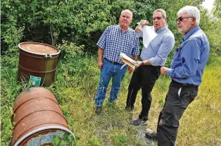  ?? BILL LACKEY / STAFF ?? Bob Rule (center), from the “potential responsibl­e party” group, German Twp. trustee Rodney Kaffenbarg­er (left) and Larry Ricketts go over the layout for the Tremont City Barrel Fill Wednesday. The barrels pictured were empty but used during testing.