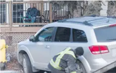  ??  ?? A man sits on a porch watching an SUV being removed from the scene of a multi-vehicle accident near Sherwood Drive and McIntyre Street.