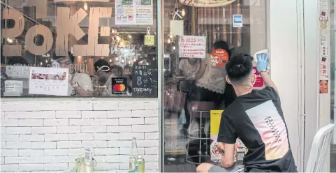  ?? BLOOMBERG ?? A man wipes a glass door after removing notes supporting the pro-democracy movement at a restaurant at Causeway Bay, Hong Kong on Thursday.