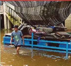  ?? NSTP PIC BY NIK ABDULLAH NIK OMAR ?? Noraman Ismail placing his belongings on a raft as floodwater­s rise at his house in Kampung Tersang, Rantau Panjang, yesterday.