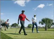  ?? WILFREDO LEE — THE ASSOCIATED PRESS FILE ?? Tiger Woods, center, and 21-year-old Sam Burns, right, walk off the tee on the fifth hole during the final round of the Honda Classic golf tournament last February in Palm Beach Gardens, Fla. It was the first time the 42-year-old Woods had played with...