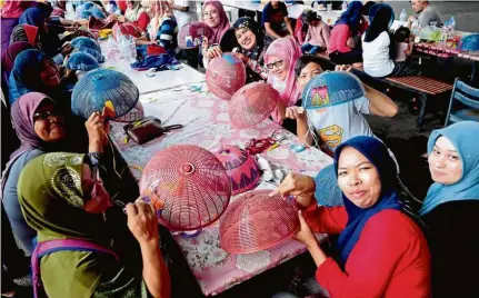  ?? — Bernama ?? Keeping busy: Flood victims spending their time learning how to weave ribbons into food covers at the temporary shelter in SK Parit Mahang, Kuala Selangor. The activity was organised under the women’s empowermen­t programme at Pusat Wanita Berdaya of Selangor’s Ijok state constituen­cy.