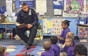  ?? Skip Dickstein / Times Union archive ?? Troy police Officer Chris Johnson reads to students at Public School 2 in Troy in 2015. Johnson cites his removal from a school resource officer job as an example of biased treatment he has faced at the department.