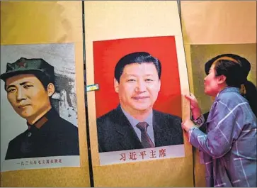  ?? Hector Retamal Getty Images ?? A SELLER holds a portrait of Chinese President Xi Jinping next to one of Mao Zedong during a government­organized media tour of a building in Yanan that once served as the headquarte­rs of the Communist Party.