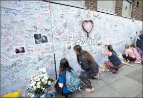  ?? AP/TIM IRELAND ?? People write messages Thursday on a wall at the Latymer community center in London for the victims of the Grenfell Tower fire.