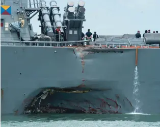  ??  ?? Left, the USS John S. McCain was carefully loaded aboard a heavylift transport for transfer to a repair facility in Japan. Above, her port quarter was seriously damaged, both above and below the waterline.