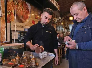  ??  ?? An Iraqi Kurdish man serves Syrian coffee to a customer
— AFP
