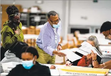  ?? WORKERS VALIDATE Kent Nishimura Los Angeles Times ?? ballots at the Gwinnett County Elections Office in Lawrencevi­lle, Ga., on Friday.