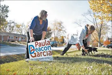  ?? STACEY WESCOTT/CHICAGO TRIBUNE ?? Kerry Senesac catches her dog, Bella, while Paula Deacon Garcia collects her campaign yard sign Friday in Lisle.