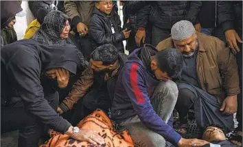  ?? Fatima Shbair Associated Press ?? IN RAFAH on Tuesday, Gazans mourn relatives killed in Israel’s bombardmen­t. Airstrikes in the southern Gaza Strip town destroyed an apartment and several houses, killing at least 15 people, hospital officials said.