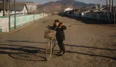  ??  ?? A boy pushes a bicycle on a street on the outskirts of the industrial city of Chongjin on North Korea’s northeast coast.