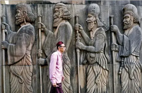  ??  ?? A Parsi man walks past a wall of a Parsi fire temple featuring huge carvings of ancient priests in Mumbai on Monday. REUTERS