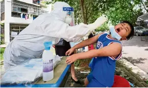  ?? — AFP ?? All in a day’s work: A medical worker taking a swab sample from a child to be tested for Covid-19 in Wuhan.