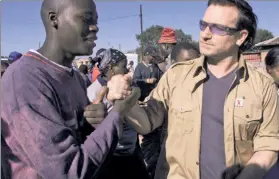  ??  ?? ROADSHOW: U2 frontman Bono chats with residents in the impoverish­ed South African town of Soweto during a 2002 tour to raise AIDS awareness.