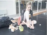  ??  ?? Heather Ogden removes tape from her feet after rehearsal. She will play the lead role of Princess Aurora in The Sleeping Beauty.