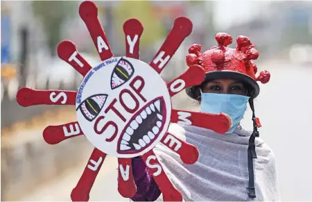  ??  ?? A volunteer in Chennai holds a placard to raise awareness about the coronaviru­s during an India-wide lockdown as a preventive measure against COVID-19.