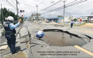  ?? Jiji Press/AFP ?? Policiais checam cratera aberta em rua na região norte de Osaka após o tremor