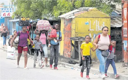  ?? REUTERS ?? Residents carry their belongings as they flee their homes due to ongoing gun battles between rival gangs in Port-au-Prince on Monday.