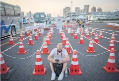  ?? AFP ?? A man looks at his mobile phone outside the Olympic media centre in Tokyo.