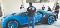  ?? ?? COOL ₱165-M WORTH – Agents of the Customs Intelligen­ce and Investigat­ion Service (CIIS) seize a blue Bugatti Chiron, which had been the object of widespread search for allegedly unpaid duties and taxes. (Photo from CIIS)