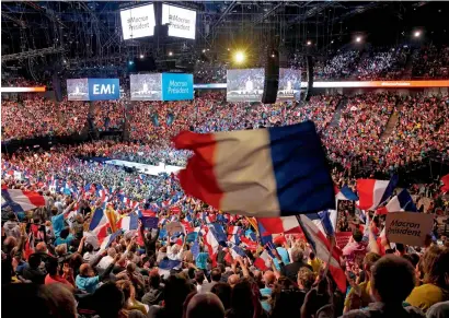  ?? AFP ?? Supporters of Emmanuel Macron wave flags during a campaign meeting at the Bercy Arena in Paris on Monday. —