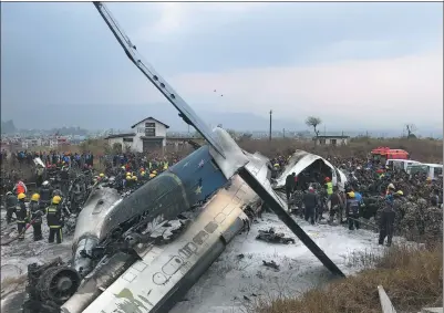  ?? NAVESH CHITRAKAR / REUTERS ?? Wreckage of a US-Bangla Airlines passenger plane is pictured as rescue workers operate at Nepal’s Tribhuvan Internatio­nal Airport in Kathmandu, Nepal, on Monday.