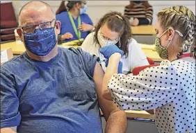  ?? Lori Van Buren / Times Union ?? High school nurse Racheal Thomas administer­s the Moderna COVID-19 vaccine to elementary school lunch monitor David Fortuin at Watervliet Junior-senior High School on Thursday in Watervliet.