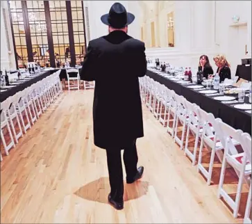  ?? Photograph­s by Michael Robinson Chavez Los Angeles Times ?? RABBI MOSHE GREENWALD walks between tables set for the nearly 240 guests at the Jewish Community Center-Chabad of Downtown Los Angeles’ Seder meal, held this year in a ballroom at the Alexandria Hotel.