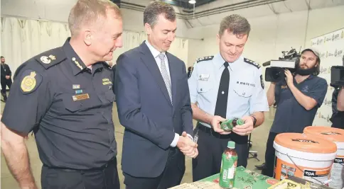  ?? — AFP photo ?? Keenan looks at a bottle of green tea containing methamphet­amine precursor chemicals with Australian Border Force (ABF) Acting Commission­er Michael Outram (left) and Australian Federal Police (AFP) Commission­er Andrew Colvin (right) in Sydney.