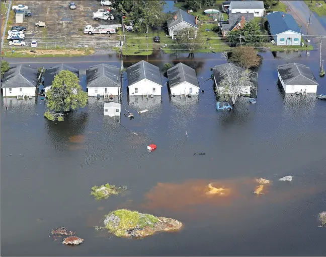  ?? GERALD HERBERT/AP ?? Floodwater­s from Hurricane Florence surrounds homes in Dillon, S.C. Scientists say climate change likely boosted rainfall totals for both Florence and 2017’s Harvey.