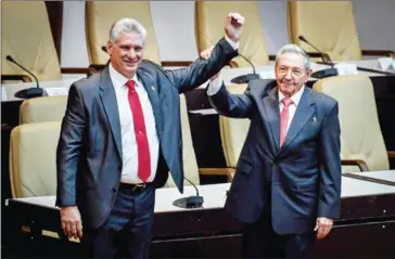  ?? ADALBERTO ROQUE/AFP ?? Outgoing Cuban President Raul Castro (right) raises the arm of Cuba’s new President Miguel Diaz-Canel after he was formally named by the National Assembly, in Havana on Thursday.